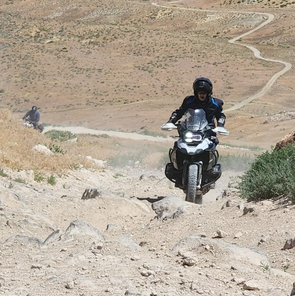 Adventure motorcycle training: Student riding up a rocky hill on a motorcycle