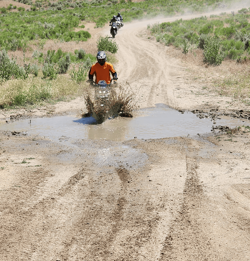 Riders going through a large, muddy puddle in idaho.